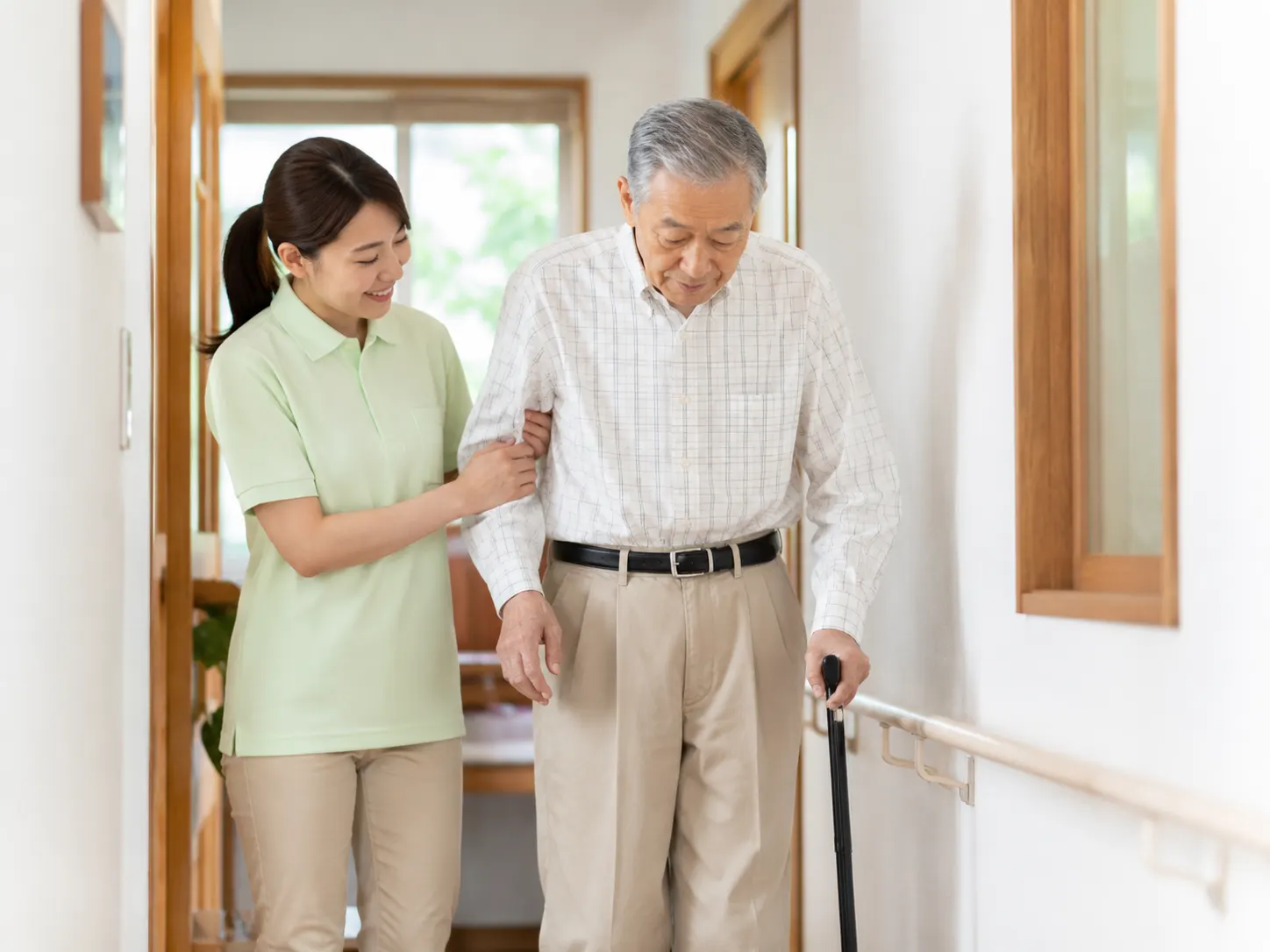 室内の手すり沿いで歩行を介助する訪問介護スタッフ